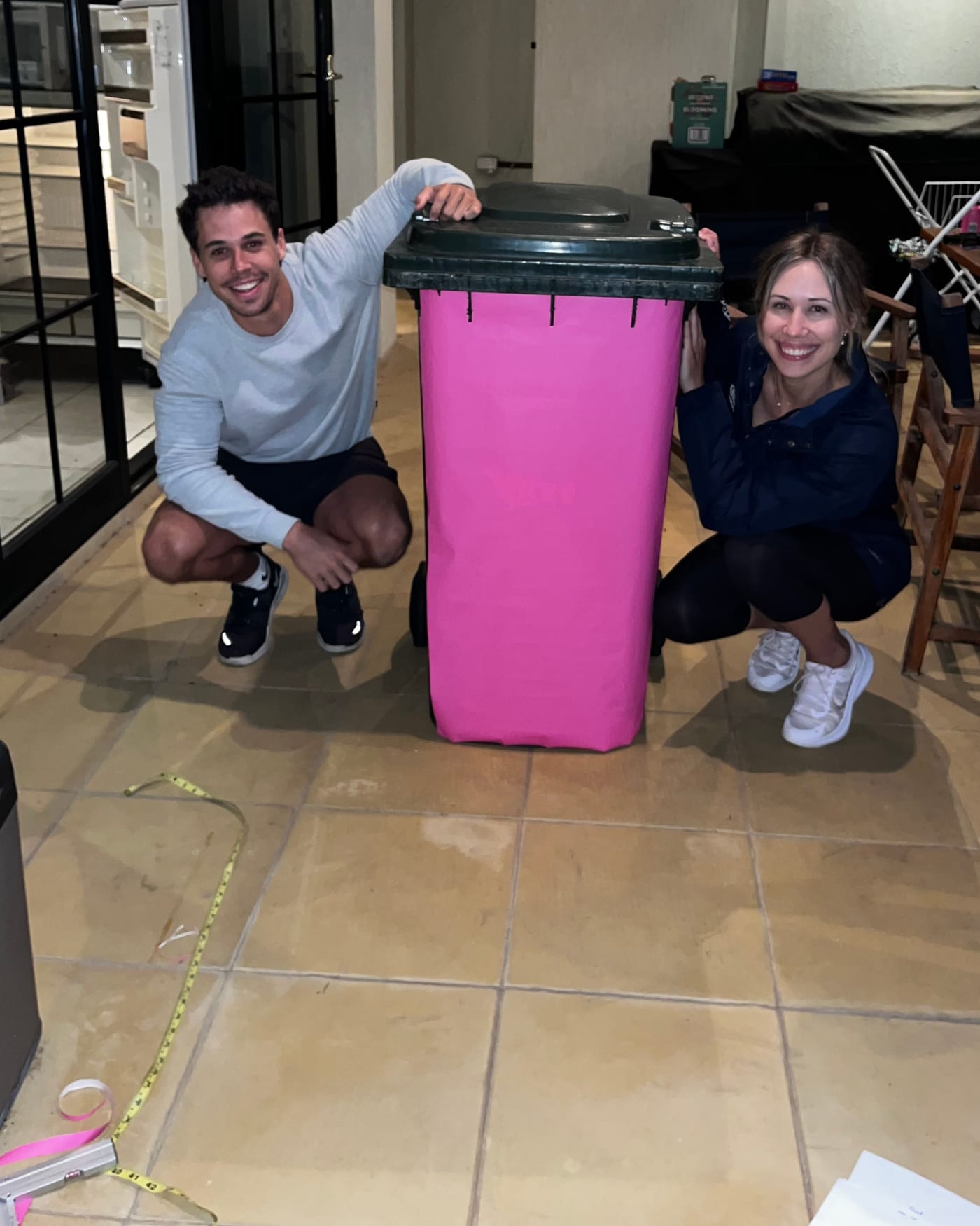 The founders crouched either side of an early pink prototype wrap on a bin, tape measure on the floor